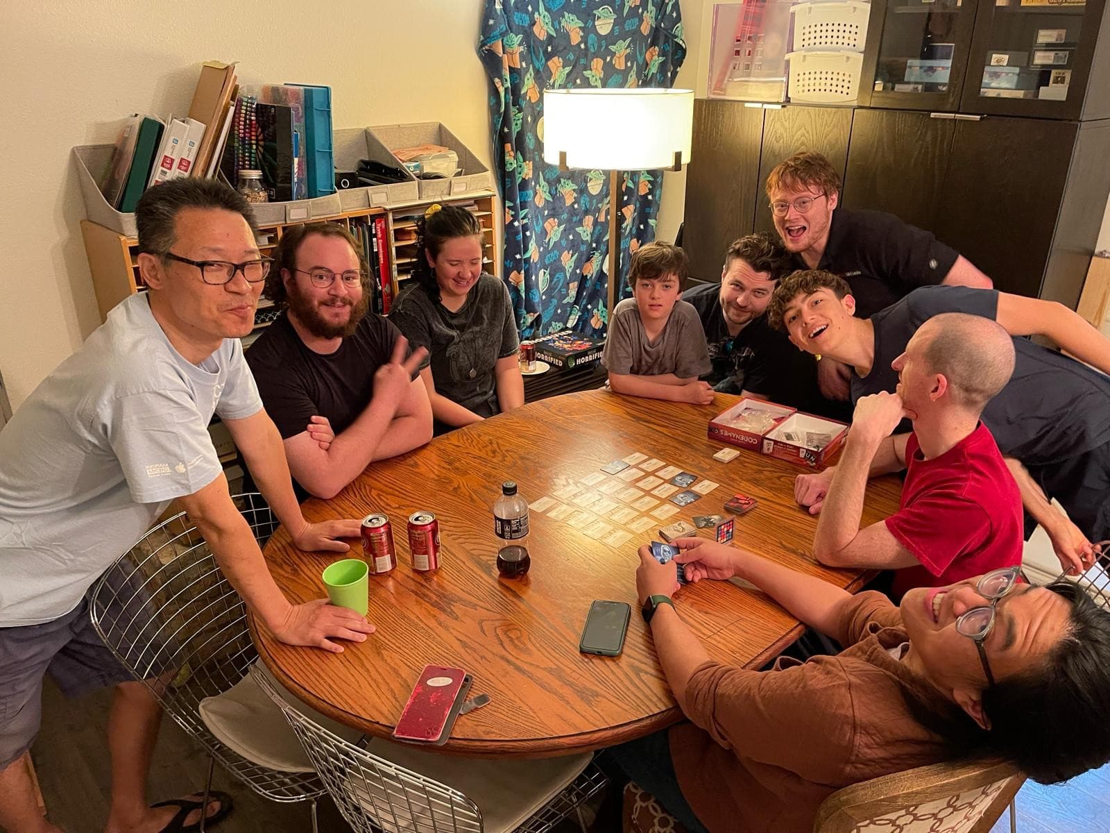 Cruce laughing with a crowded table of players during a game of Codenames at South Austin Games.