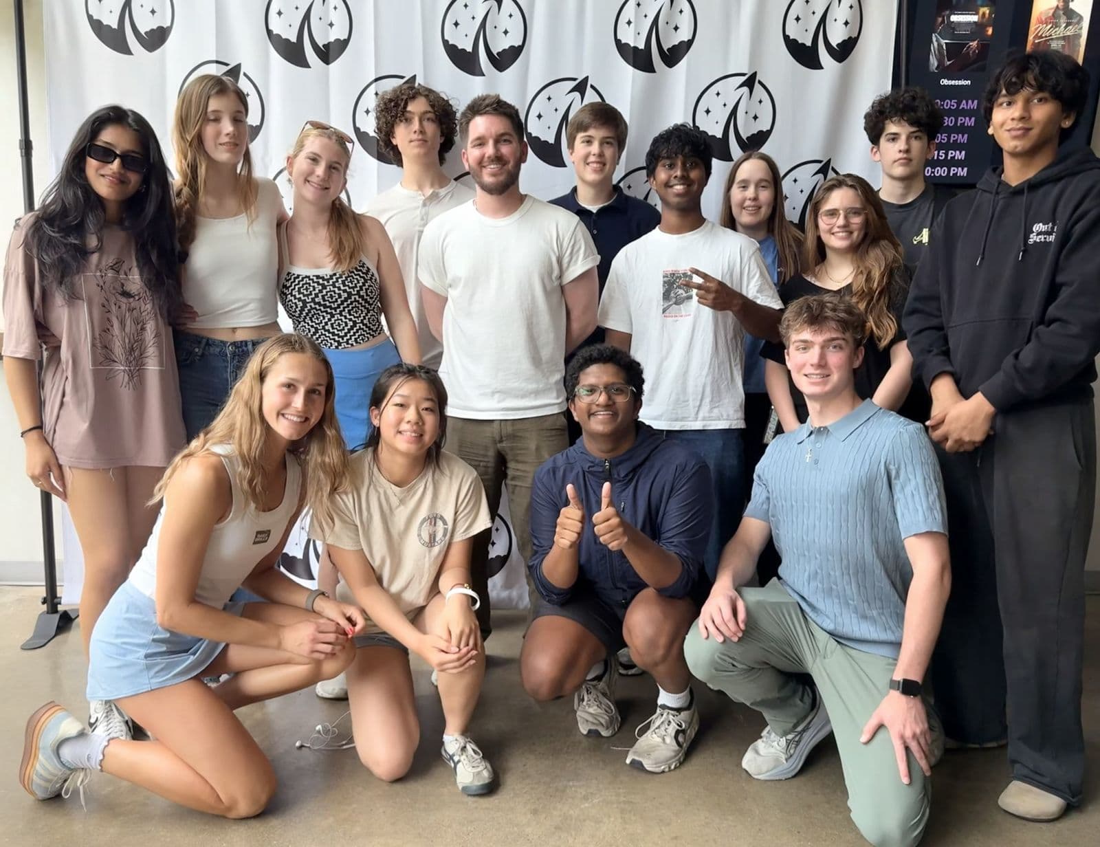 Cruce, curly-haired in the back row, with the cast at a Limitless premiere in Austin, posed in front of a logo backdrop.
