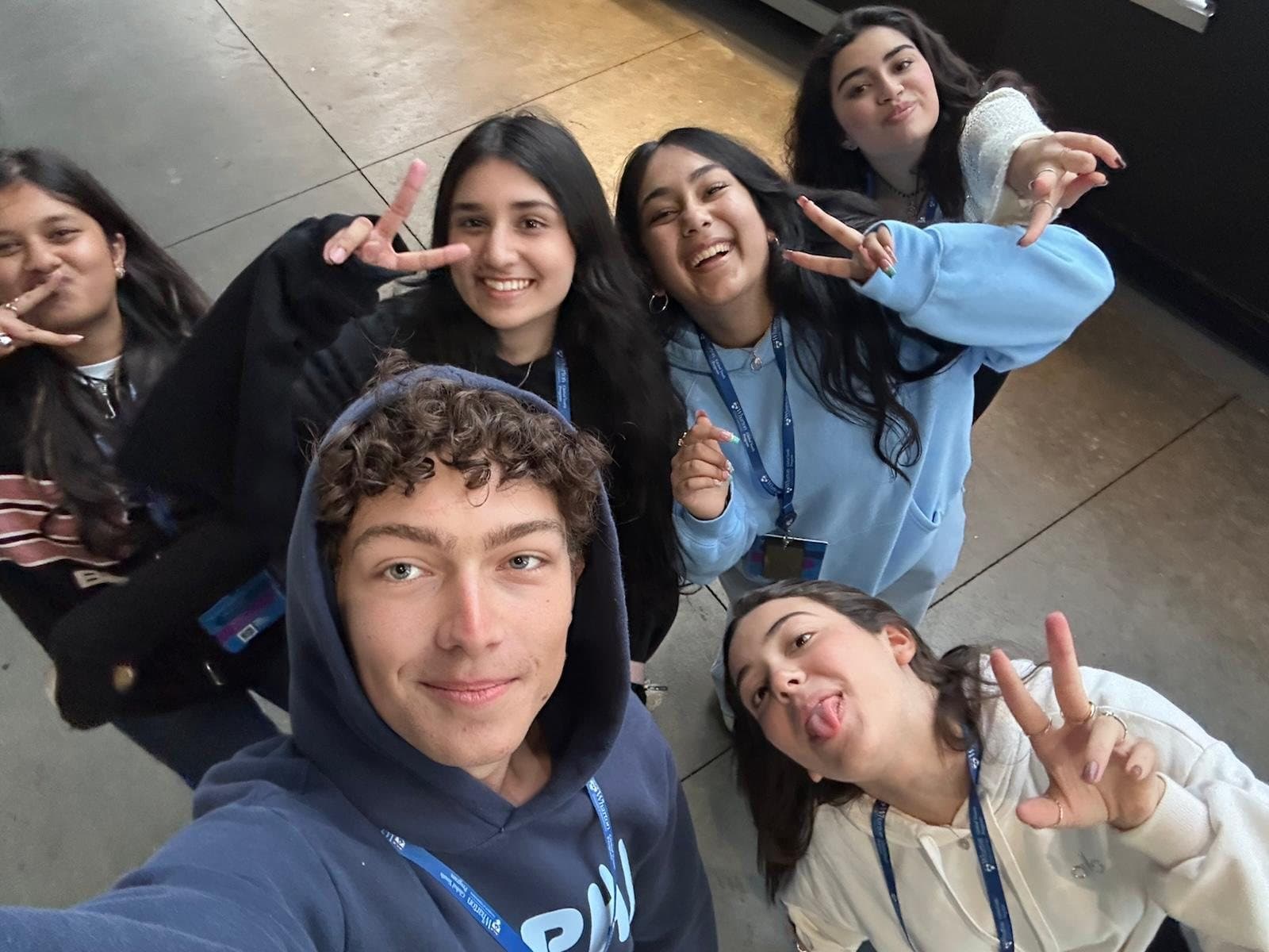 Cruce in a navy hoodie taking a selfie with five Wharton Global Youth classmates, all wearing program lanyards.